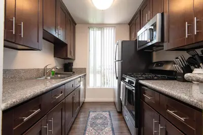 a kitchen with wooden cabinets and a stove top oven at Modern Escape in Hollywood with Rooftop & City Views in Los Angeles