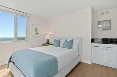 a white bedroom with a large bed with blue pillows at The Amethyst Retreat Ocean Marina Panoramic View in Los Angeles