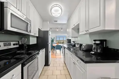 a kitchen with white cabinets and black counter tops at The Amethyst Retreat Ocean Marina Panoramic View in Los Angeles