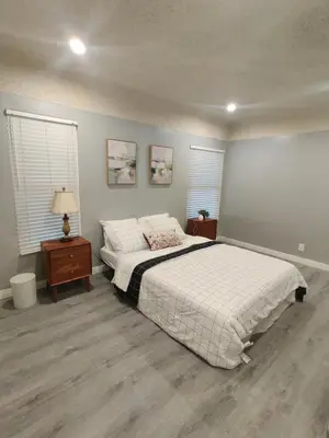 a bedroom with a large bed and two windows at sofi intuit cozy home free parking queen beds in Inglewood