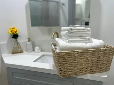 a basket of towels on a bathroom counter with a sink at LA Modern Street View Glass Window 2BR in North Sherman Way