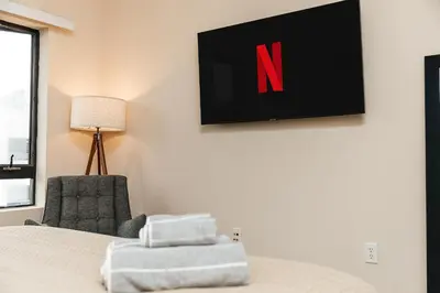a bedroom with a bed and a chair and a television at Stunning 2 bedroom near by The Grove in Los Angeles