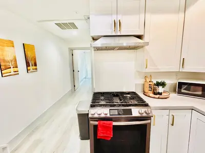 a kitchen with white cabinets and a stove top oven at Newly Built Modern Central 2B On Sherman with Free Parking in North Sherman Way