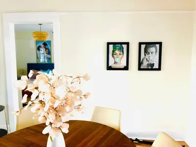 a vase of flowers on a table with pictures on the wall at Honeywood in Hollywood! in Los Angeles