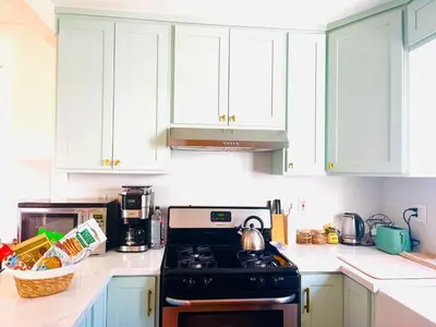 a kitchen with white cabinets and a black stove at Honeywood in Hollywood! in Los Angeles