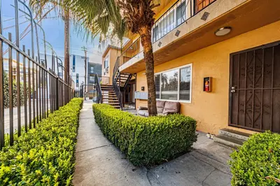 a building with a tree and bushes next to a sidewalk at Relaxing Studio 12 in Los Angeles