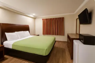 a hotel room with a bed and a flat screen tv at Casa Blanca Hotel - Corona in Corona