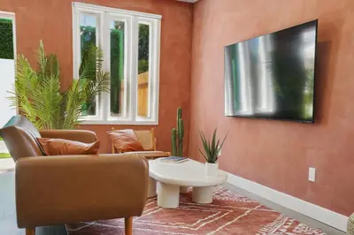a living room with a couch and a tv on a wall at La Tierra House 15 Min to Beach Movie Lounge in Hawthorne