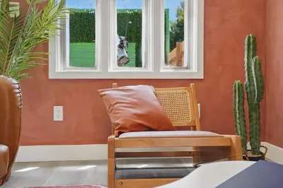 a chair sitting under a window in a room with cactus at La Tierra House 15 Min to Beach Movie Lounge in Hawthorne