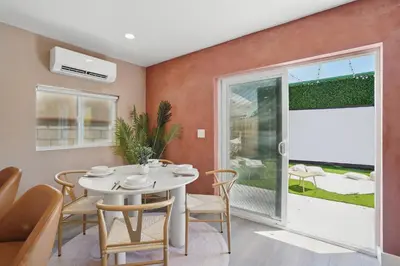 a dining room with a white table and chairs and a window at La Tierra House 15 Min to Beach Movie Lounge in Hawthorne