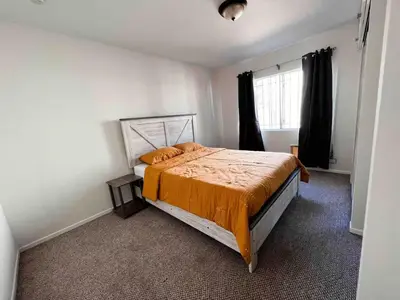 a bedroom with a bed with an orange comforter and a window at Urban Casita in Los Angeles
