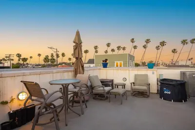 a patio with chairs and tables and an umbrella at Seventh Shore Stylish Seal Beach Home w Elevator Fireplace Bold Design in Seal Beach