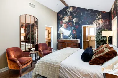 a bedroom with a large bed and two chairs at Seventh Shore Stylish Seal Beach Home w Elevator Fireplace Bold Design in Seal Beach