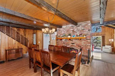 a dining room with a wooden table and a brick wall at Acorn Acres - Lake Views for 8 in Lake Arrowhead