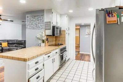 a kitchen with white cabinets and a refrigerator at 7 Mi to Dtwn Poolside Paradise in Bakersfield! in Bakersfield