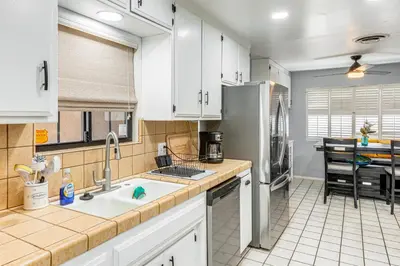 a kitchen with a sink and a refrigerator at 7 Mi to Dtwn Poolside Paradise in Bakersfield! in Bakersfield