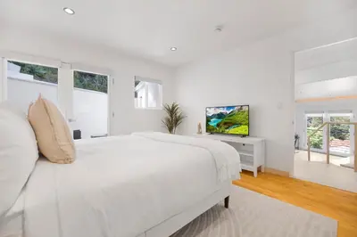 a white bedroom with a white bed and a tv at Belden View in Los Angeles