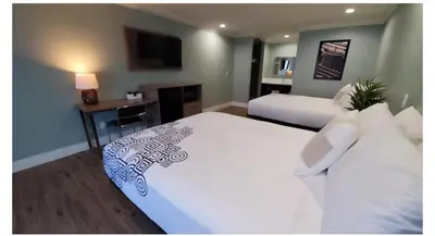 a bedroom with two beds and a desk with a television at Crestridge Inn Near LAX, SoFi Stadium & Intuit Dome in Inglewood