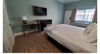 a bedroom with a bed and a desk and a television at Crestridge Inn Near LAX, SoFi Stadium & Intuit Dome in Inglewood
