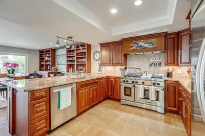 a kitchen with wooden cabinets and a stove top oven at Chic Coastal Home with Outdoor Oasis in Oxnard! in Oxnard