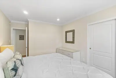a white bedroom with a bed and a mirror at The Andalusite - Oceanfront Steps from the Sand in Los Angeles