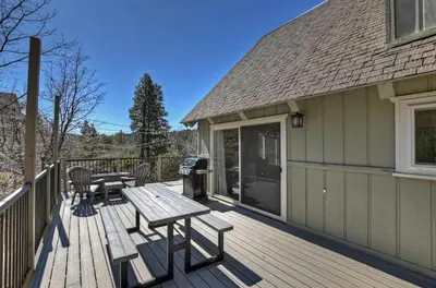 a wooden deck with a picnic table and chairs at Bow N Arrow Lodge For 8 in Lake Arrowhead