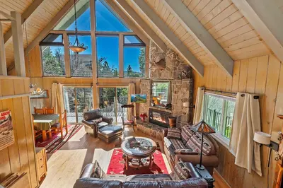 a living room with leather furniture and a stone fireplace at Bow N Arrow Lodge For 8 in Lake Arrowhead