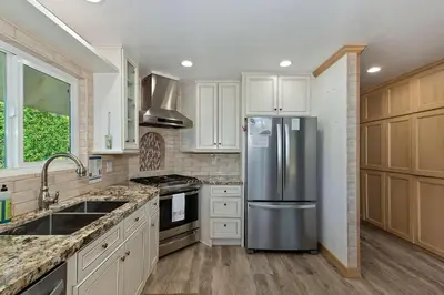 a kitchen with white cabinets and a stainless steel refrigerator at Casa Del Lago - Spacious 4 Story Gated Home in Lake Arrowhead