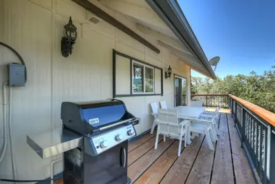 a grill on a deck with a table and chairs at Casa Del Lago - Spacious 4 Story Gated Home in Lake Arrowhead