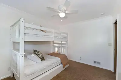 a bedroom with a white bunk bed and a ceiling fan at Casa Del Lago - Spacious 4 Story Gated Home in Lake Arrowhead