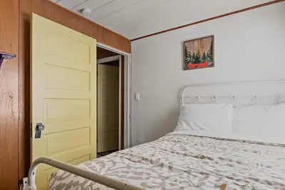 a bedroom with a white bed and a yellow door at Happy Bear Cabin - Hike Bike & More in Big Bear Lake