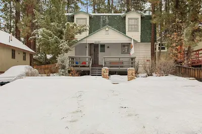 a house with a snow covered driveway in front of it at Happy Bear Cabin - Hike Bike & More in Big Bear Lake