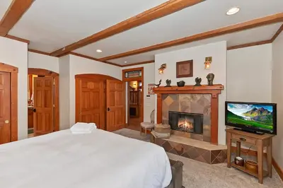 a bedroom with a fireplace and a bed and a television at Matternhorn Peak Lodge - For 10 in Lake Arrowhead