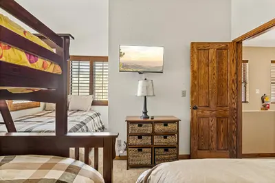 a bedroom with two beds and a wooden door at The Adler's Nest - Lakefront with Pool Spa and Summer Dock in Big Bear Lake