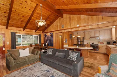 a living room with two couches and a kitchen at The Lazy Bear Cabin - For 6 in Crestline