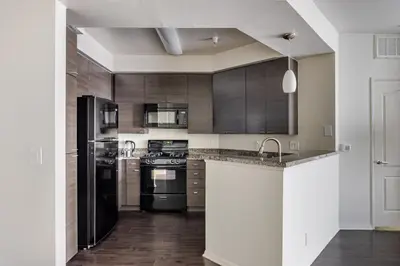 a kitchen with black appliances and wooden cabinets at Blueground Venice pool AC nr beach LAX-1330 in Los Angeles