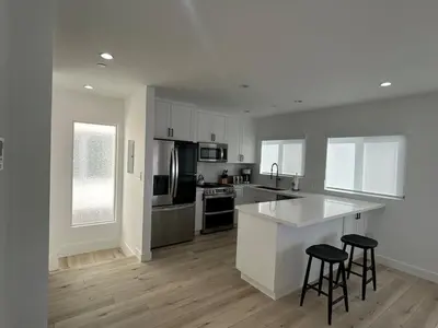 a kitchen with white cabinets and two bar stools at MB Modern Sand Section Sea View in Manhattan Beach