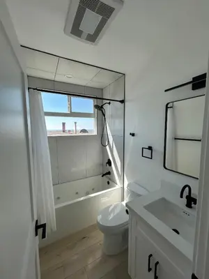 a white bathroom with a toilet and a mirror at MB Modern Sand Section Sea View in Manhattan Beach