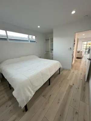 a white bedroom with a large bed and a wooden floor at Manhattan Beach Modern Panoramic Sea View in Manhattan Beach