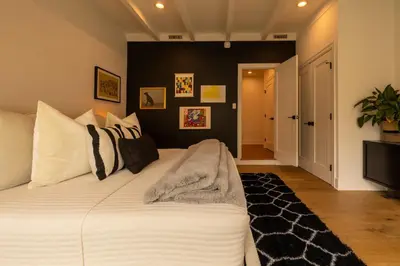 a bedroom with a large bed with black walls at Hauser House, Modern Artful Spanish-style Bungalow in Los Angeles