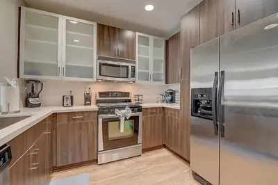 a kitchen with wooden cabinets and stainless steel appliances at Sexy One Bedroom Apartment - Pool View & Parking in Los Angeles