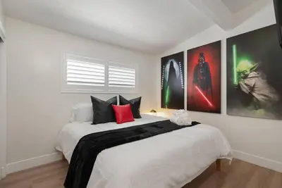 a bedroom with a large white bed with posters on the wall at Lightsaber Lounge-Hot Tub-Billiards-10mnstoDisney in Anaheim