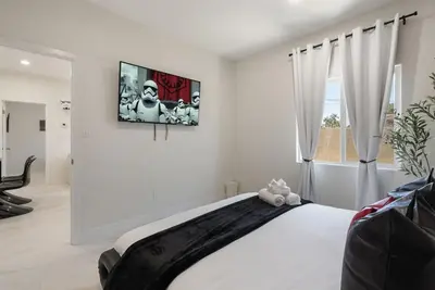 a bedroom with a large white bed with a picture on the wall at Lightsaber Lounge-Hot Tub-Billiards-10mnstoDisney in Anaheim