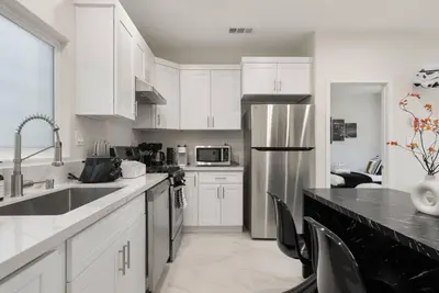 a kitchen with white cabinets and a stainless steel refrigerator at Darth Vaders Lair - 10 mins to Disney - Sleeps 6 in Anaheim