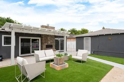 a patio with chairs and a table on a lawn at Stunning Retro Beach Oasis, Dual Living, Pool in Long Beach