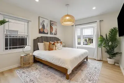 a bedroom with a large bed and two windows at Stunning Retro Beach Oasis, Dual Living, Pool in Long Beach
