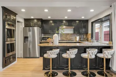 a kitchen with black cabinets and white bar stools at Designer Dream- Pool and spa- Game Room- Sleeps 10 in Los Angeles