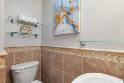 a bathroom with a toilet and a painting on the wall at Refreshing Escape- Hot Tub- Games- Sleeps 10 in Long Beach