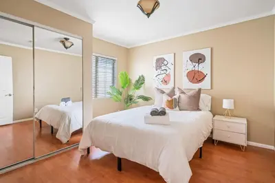 a bedroom with a large white bed and a mirror at Serene Yard Porch at Signal Hill - Close to the Beach in Signal Hill