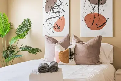 a bedroom with a white bed with pillows and plants at Serene Yard Porch at Signal Hill - Close to the Beach in Signal Hill